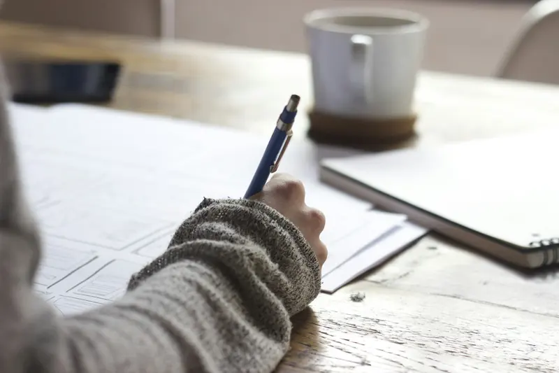 Author writing a manuscript by hand at a wooden desk